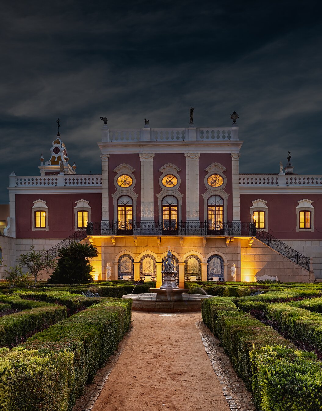 Palácio de Estoi Rococo façade illuminated at dusk with formal gardens