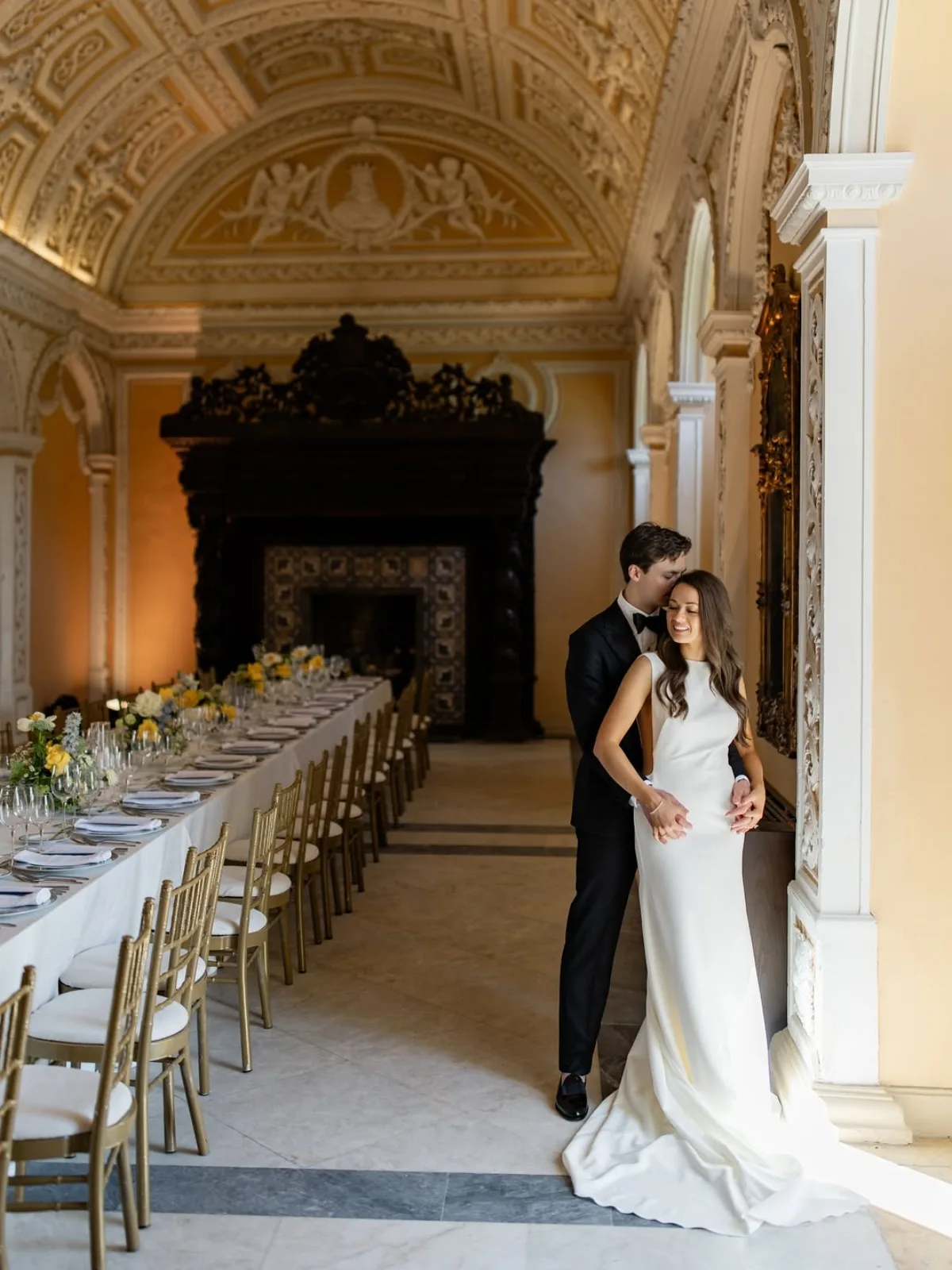 Dinner table laid beneath a carved chimneypiece and azulejo walls in a palace hall