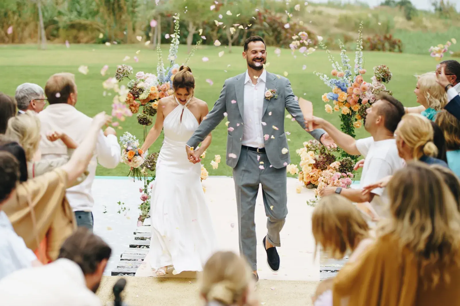 Petals thrown over the couple as they leave the lawn ceremony between pastel arrangements