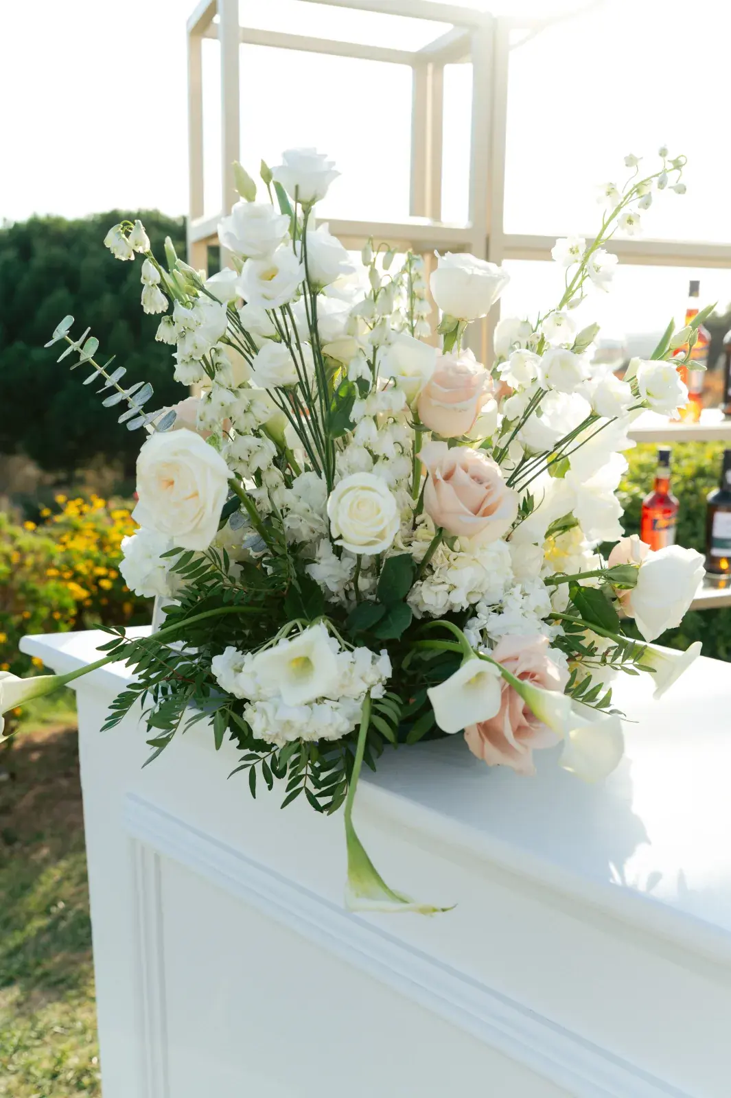 White and blush arrangement with calla lilies on the garden bar at golden hour