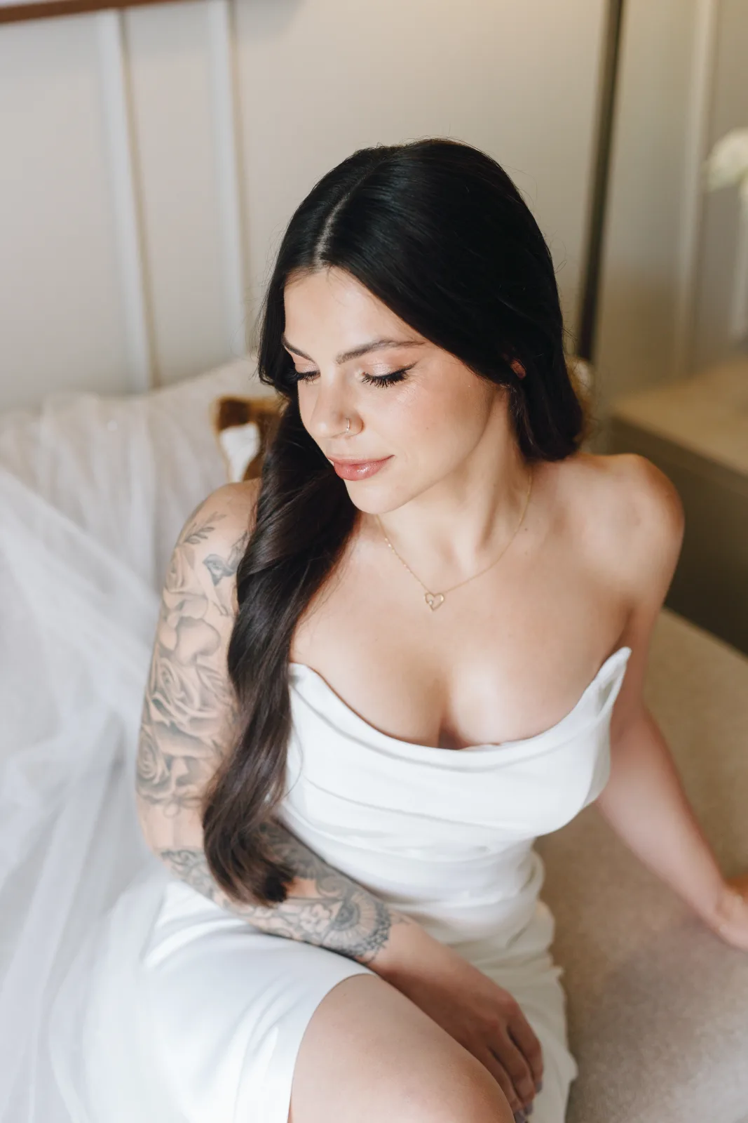 Bride seated in window light in a draped column gown, quiet minutes before the first look
