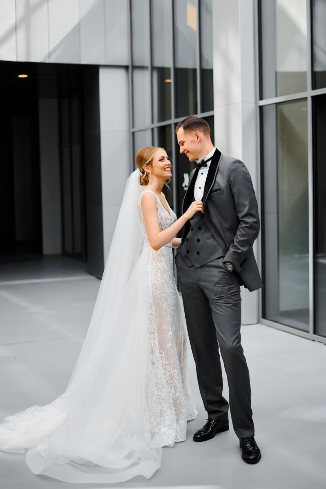 Bride and groom smiling together outside the hotel's stone-and-glass facade before the ceremony