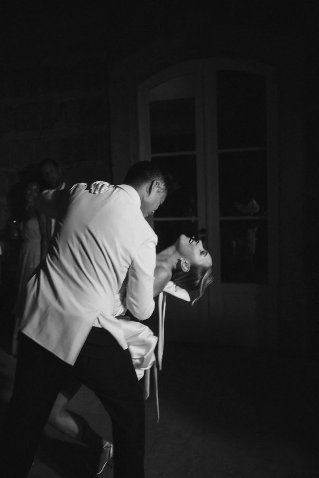 Late-night dip on the dance floor, doorway light cutting through the dark, in black and white